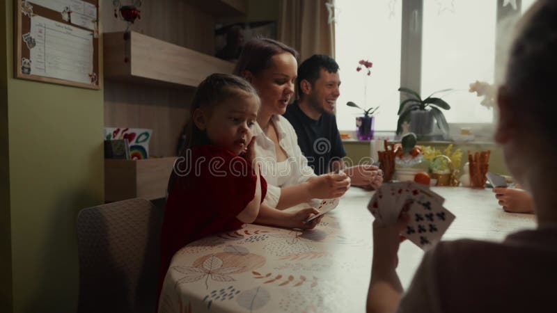 Cărți de joc de familie la domiciliu : Părinții învață fiica un nou joc stock footage