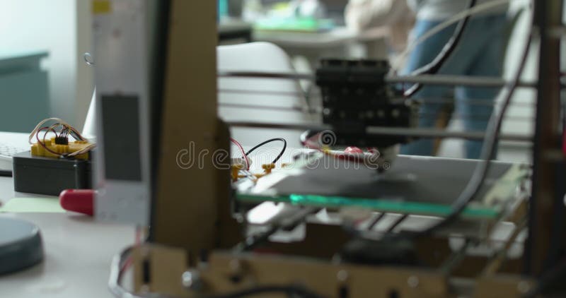 3D printer printing a prototype and engineering students stock video