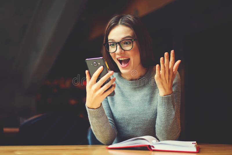 Da leitura fêmea dentro surpreendida e entusiasmado livro interessante após o trabalho foto de stock Da leitura fêmea dentro surpreendida e entusiasmado livro interessante após o trabalho foto de stock