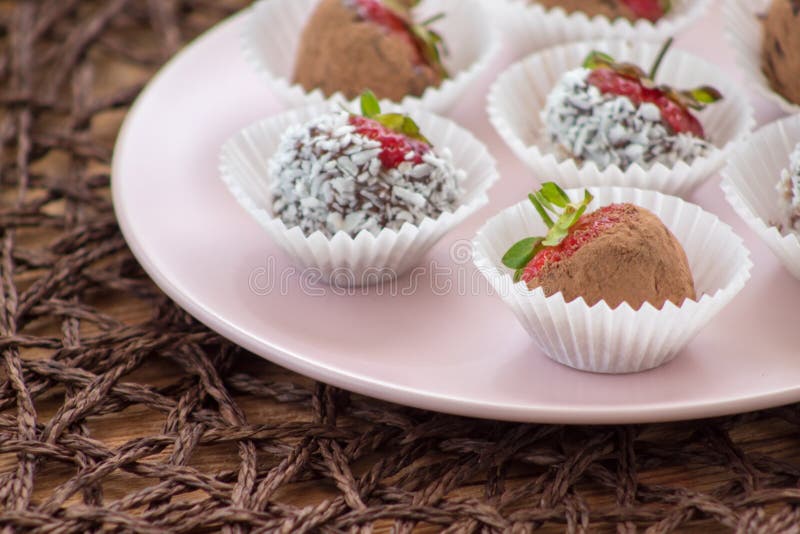 Daadwillige aardbeien bedekt met cacaopoeder en kokosvlokken op de plaat stock foto Daadwillige aardbeien bedekt met cacaopoeder en kokosvlokken op de plaat stock foto