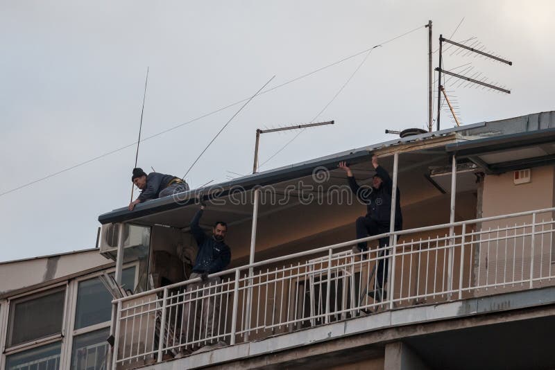 Dachdecker Dachdecker drei Männer Arbeiter Anpassung der Fliesen an der Spitze eines Wohnhauses in Renovierung und Restaurierung