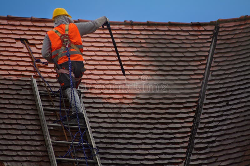 Man cleaning old tiles on the roof. Man cleaning old tiles on the roof