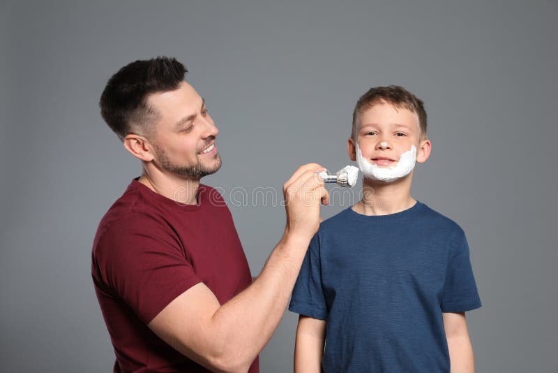 Dad applying shaving foam on son`s face