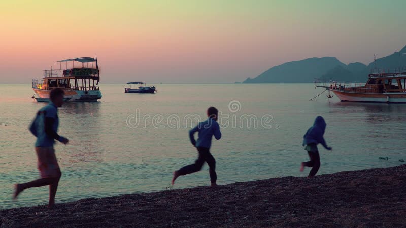 Dad with children running along the beach.