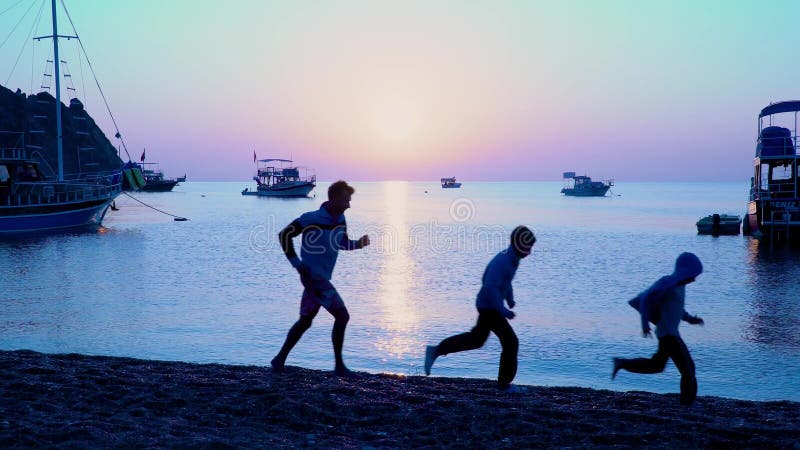 Dad with children running along the beach.