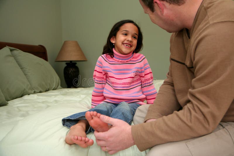 Dad tickles his daughter before she goes to bed. Dad tickles his daughter before she goes to bed