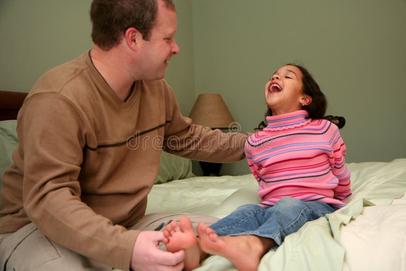 Dad tickles his daughter before she goes to bed. Dad tickles his daughter before she goes to bed