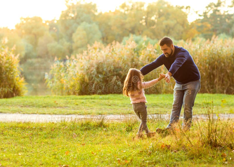 Padre e figlia in autunno parco gioco a ridere.