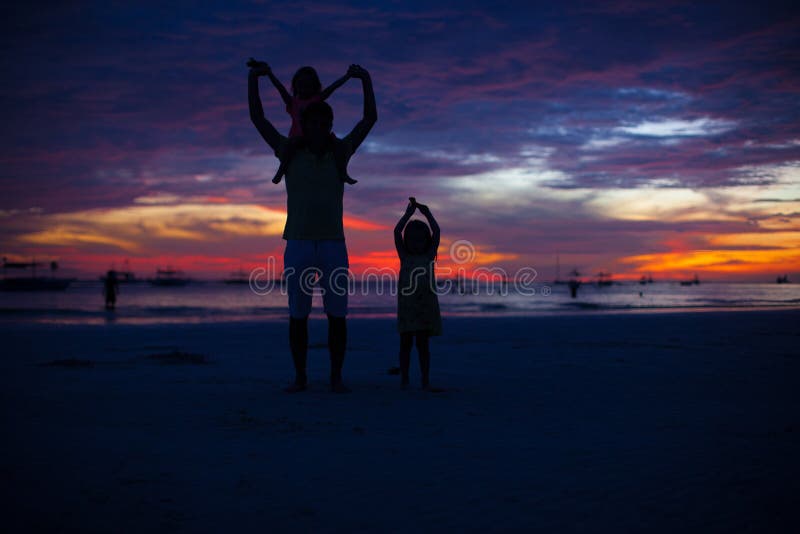 Dad and daughters silhouette in the sunset on the