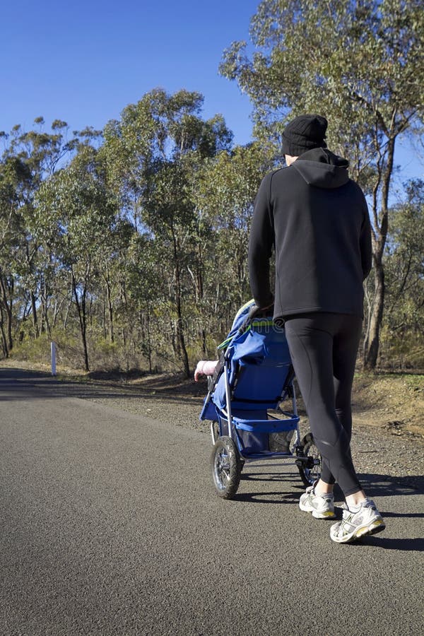 Dad jogging with baby stroller on a country road