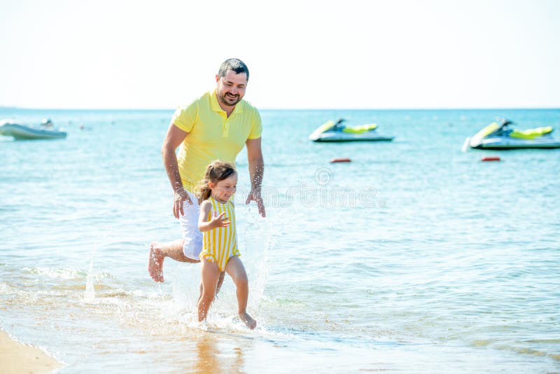 Dad and little girl play, run on the beach and fool around on the sea coast. Family vacation at sea with a child stock images Dad and little girl play, run on the beach and fool around on the sea coast. Family vacation at sea with a child stock images