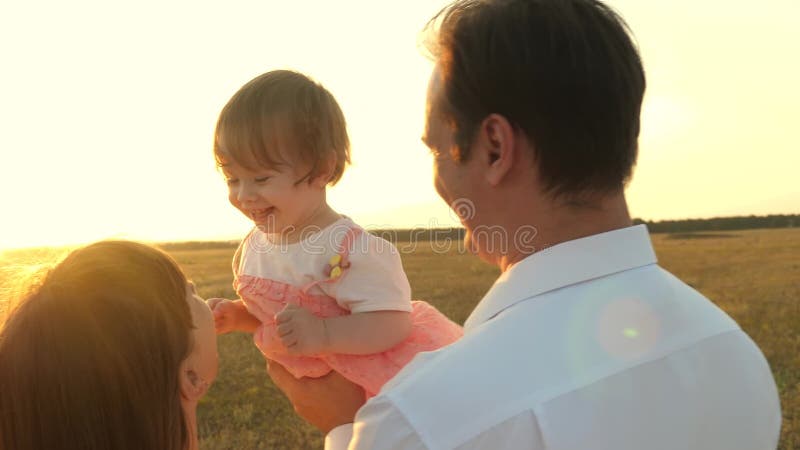 Dad and mom playing with a little daughter in her arms at sunset. family walks with a child at sunset. father playing