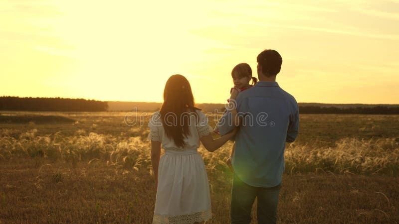 Dad and mother with their beloved daughter in their arms walk in the park at sunset. Happy child plays with father and stock photos Dad and mother with their beloved daughter in their arms walk in the park at sunset. Happy child plays with father and stock photos