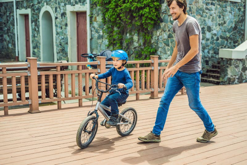 Dad Teaches Son To Ride a Bike in the Park Stoc