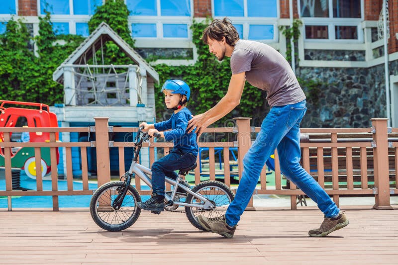 Dad Teaches Son To Ride a Bike in the Park Stoc pic