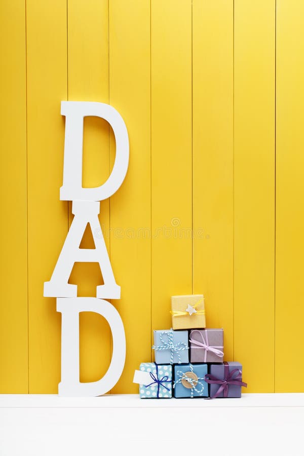 DAD text letters with gift boxes on yellow wooden background royalty free stock images DAD text letters with gift boxes on yellow wooden background royalty free stock images