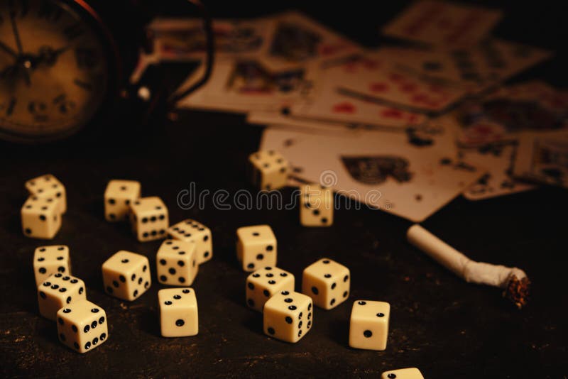 Dice,cigarettes, cards, and an abandoned alarm clock on a table in an underground casino. Dice,cigarettes, cards, and an abandoned alarm clock on a table in an underground casino.