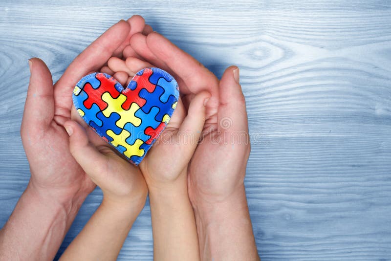 Dag för världsautismmedvetenhet, pussel eller figursågmodell på hjärta med autistiska barns och faderhänder