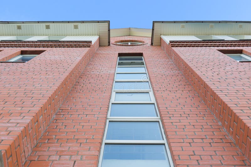 Daglichtmening van bodem aan rode baksteenvoorgevel van de moderne bouw Heldere blauwe hemel op achtergrond stock afbeeldingen Daglichtmening van bodem aan rode baksteenvoorgevel van de moderne bouw Heldere blauwe hemel op achtergrond stock afbeeldingen