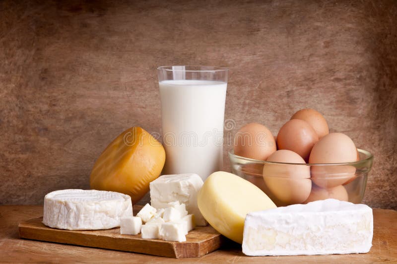 Ancora vita con latticini, latte, formaggi e uova su uno sfondo di legno.