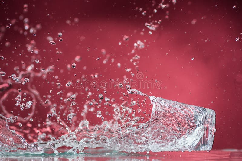 Dalende kleine glazen en het morsen van water op een blauwe achtergrond stock fotografie Dalende kleine glazen en het morsen van water op een blauwe achtergrond stock fotografie