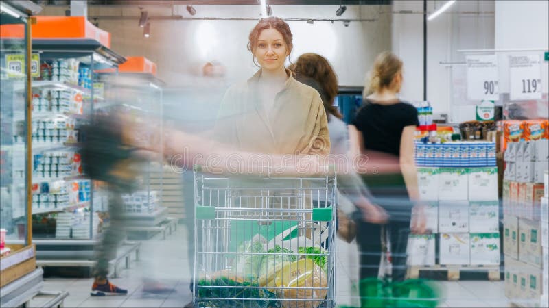 Dam i bruna lagställningar med shoppingvagnen på kylar royaltyfri bild Dam i bruna lagställningar med shoppingvagnen på kylar royaltyfri bild