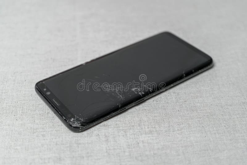 Damaged Mobile Phone with a Cracked Display on the Table Stock Image