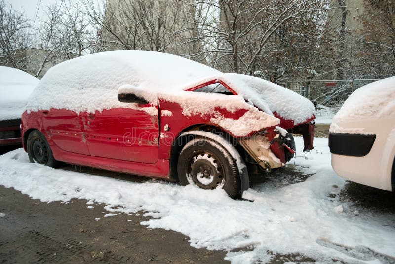 Damaged red car, with a bent hood, covered with snow, sitting in an auto service yard royalty free stock photo Damaged red car, with a bent hood, covered with snow, sitting in an auto service yard royalty free stock photo