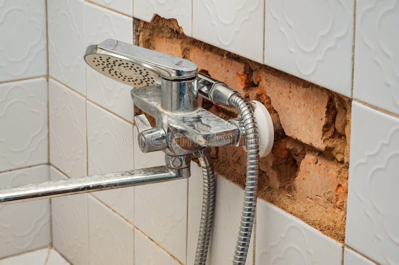 Damaged shower area shows broken tiles and brick, needing renovation and repair due to limescale. royalty free stock photo