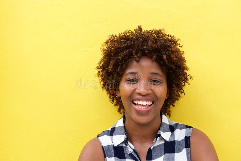 Dame africaine riant contre le mur jaune image stock Dame africaine riant contre le mur jaune image stock