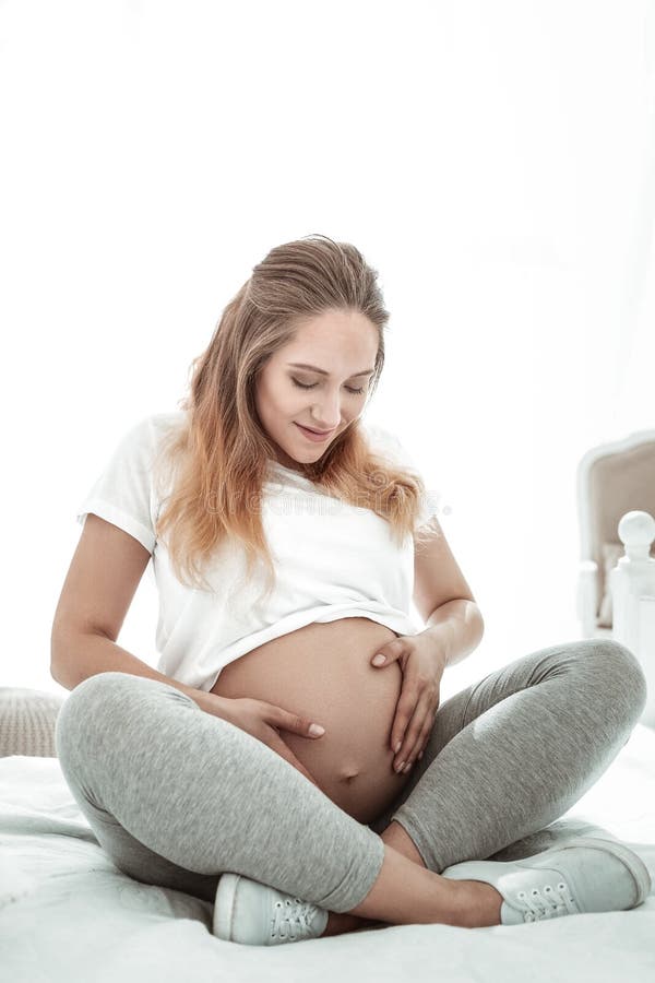 Dame agréable positive s'asseyant avec les jambes croisées et observant images libres de droits