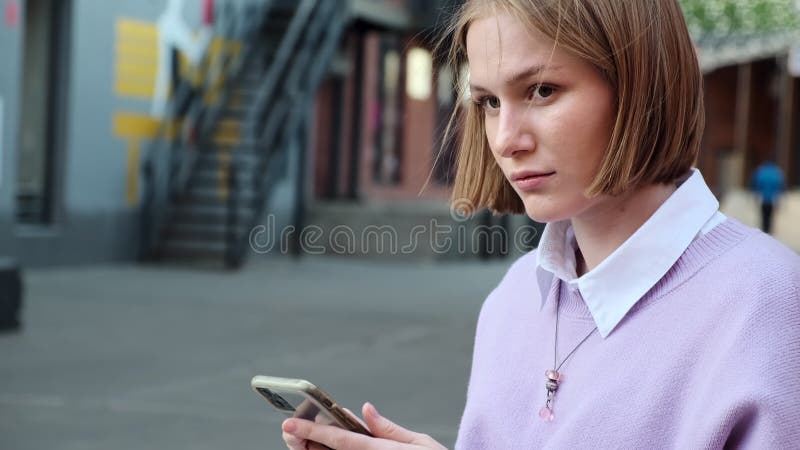 Dame blonde avec cheveux courts sur téléphone noir dans la rue banque de vidéos