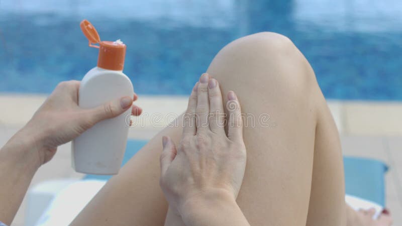 Dame die zonnebrandolie op haar benen met het masseren van bewegingen toepassen die door pool rusten