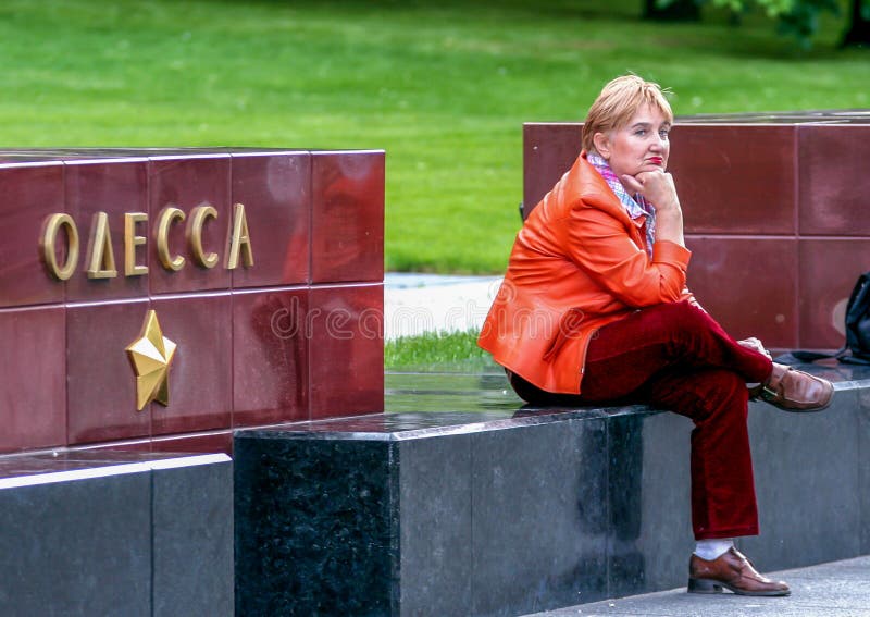 Dame im roten Sitzen im des Alexanders Garten von Moskau der Kreml Odessa-Stadtdenkmal im Moskau-Park lizenzfreie stockbilder Dame im roten Sitzen im des Alexanders Garten von Moskau der Kreml Odessa-Stadtdenkmal im Moskau-Park lizenzfreie stockbilder