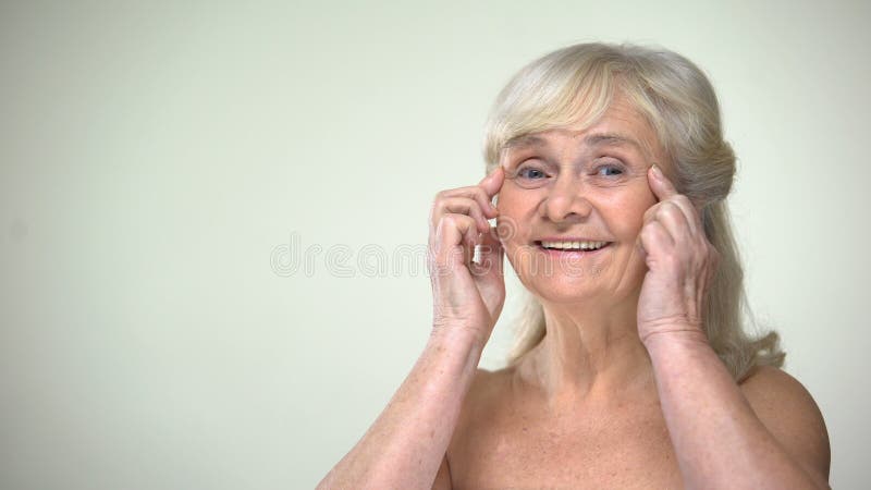 Dame pluse âgé attirante unwrinkling, souriant à la caméra, concept de vieillissement de beauté