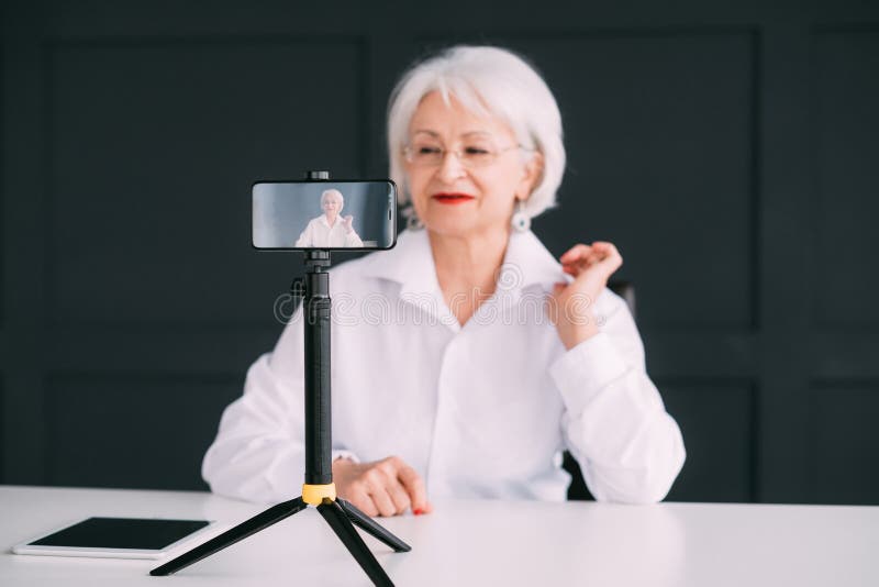 Dame supérieure d'affaires bloguant pour tirer la vidéo mobile photographie stock libre de droits Dame supérieure d'affaires bloguant pour tirer la vidéo mobile photographie stock libre de droits