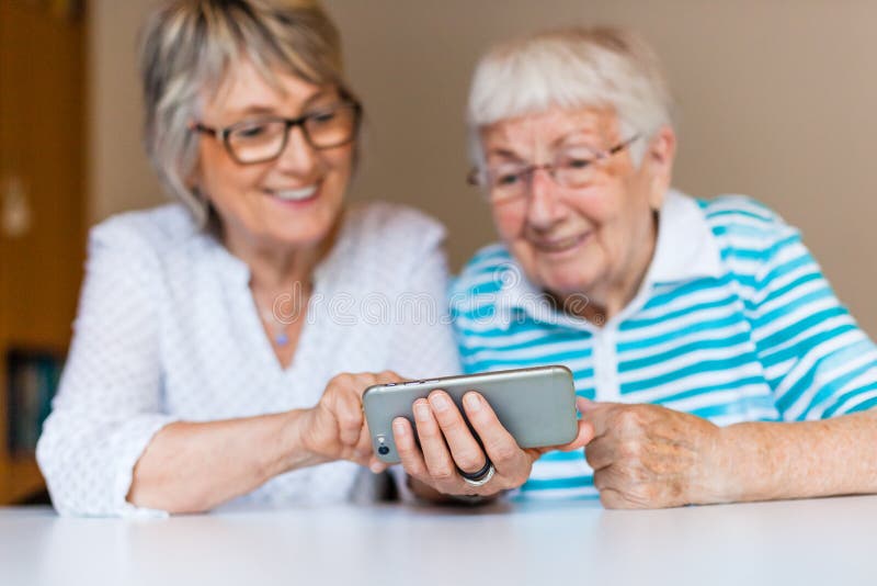 Dame supérieure utilisant le téléphone intelligent avec sa mère photos stock