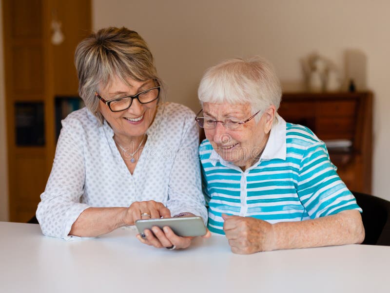 Dame supérieure utilisant le téléphone intelligent avec sa mère photographie stock libre de droits