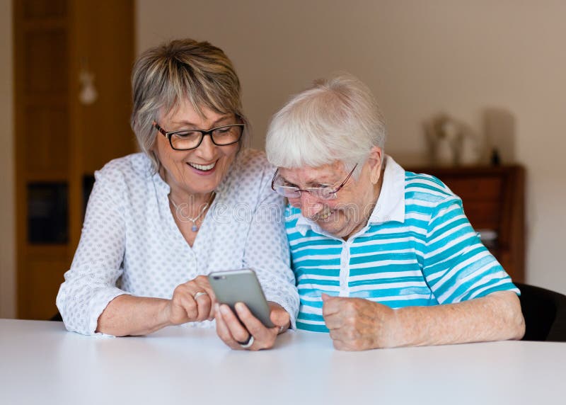 Dame supérieure utilisant le téléphone intelligent avec sa mère photos libres de droits