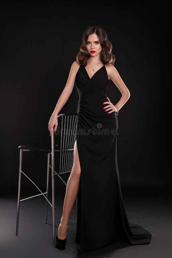Dame élégante dans la longue robe sexy avec la rétro pose onduleuse de coiffure d'isolement sur le fond de noir de studio Belle f image stock Dame élégante dans la longue robe sexy avec la rétro pose onduleuse de coiffure d'isolement sur le fond de noir de studio Belle f image stock