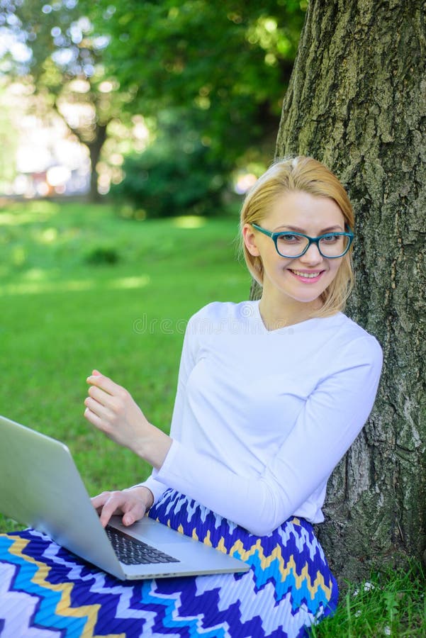 Lady freelancer working in park. Woman with laptop works outdoor, park background. Girl sit grass lean tree trunk with notebook. Wi fi network connection free access. Taking advantages of freelance. Lady freelancer working in park. Woman with laptop works outdoor, park background. Girl sit grass lean tree trunk with notebook. Wi fi network connection free access. Taking advantages of freelance.