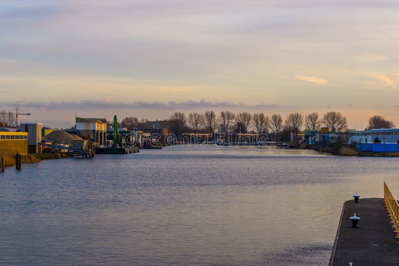 Damm mit Wasseransicht in die Stadt aan Höhle Alphen rijn, die Niederlande, Industriegebiet mit Gebäuden lizenzfreies stockfoto Damm mit Wasseransicht in die Stadt aan Höhle Alphen rijn, die Niederlande, Industriegebiet mit Gebäuden lizenzfreies stockfoto