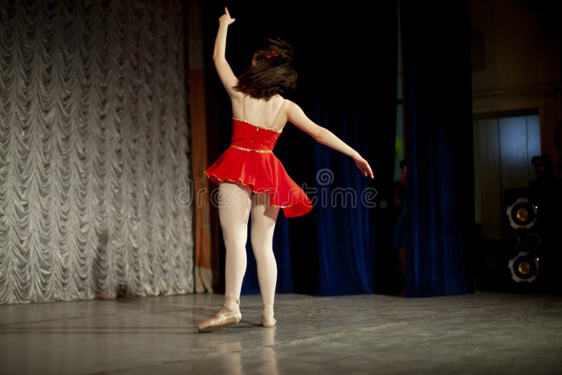 Dancer on stage from the back. Girl in a red dress, white tights and Czechs.