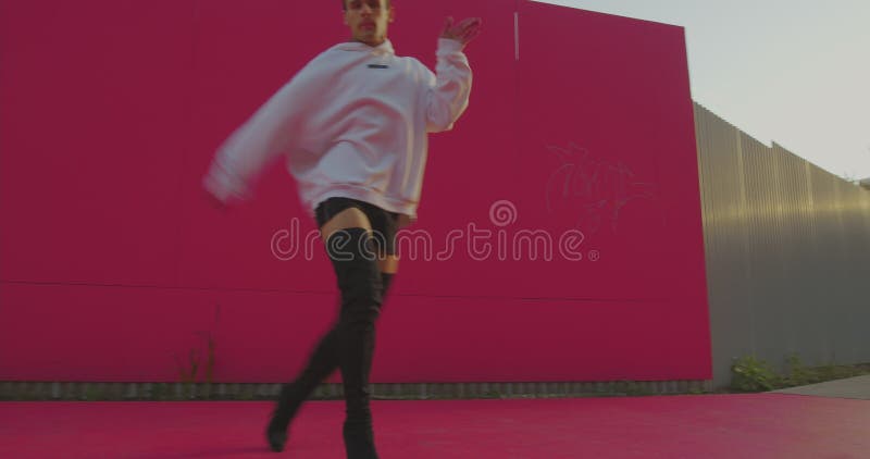 Dancing cool lgbt guy wearing heels perform graceful sexy provocative dance on street background outside in sunshine