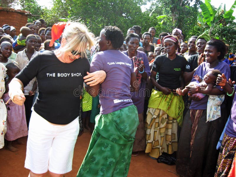 Dancing del lavoratore umanitario della donna bianca e dell'Africano per la gioia davanti ai paesani Uganda Africa Dancing del lavoratore umanitario della donna bianca e dell'Africano per la gioia davanti ai paesani Uganda Africa