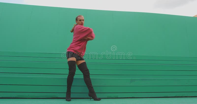 Dancing lgbt male wearing heels perform graceful passionate dance, sexy moving on green background outdoor