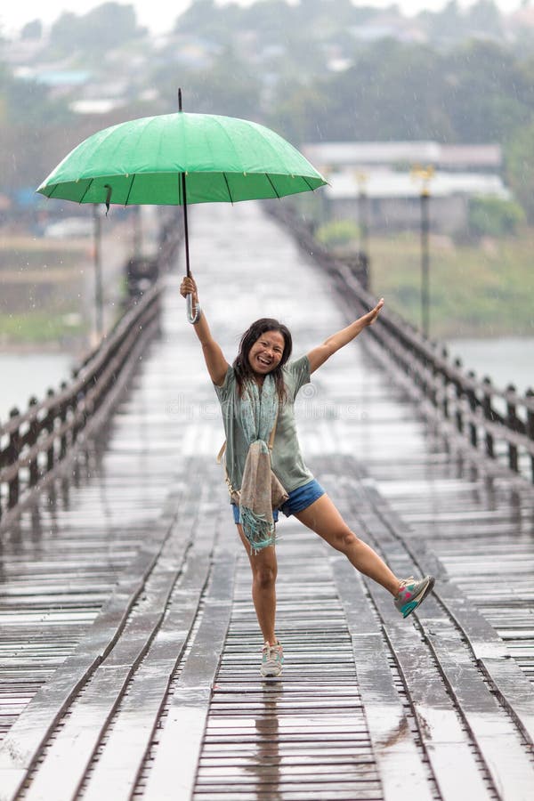 Una donna danza la pioggia cadente sul lunedi di legno ponte da, tailandia.