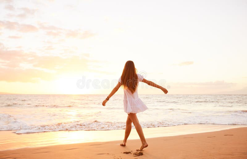 Dancing spensierato felice della donna sulla spiaggia al tramonto