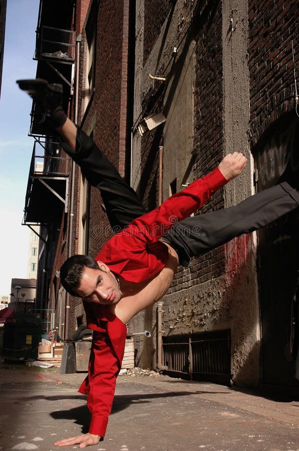 Maschio modello in rosso a ballare in un ambiente urbano.