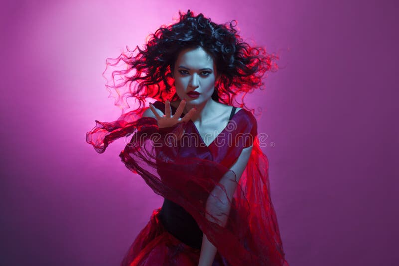 Dancing woman with flying red dress. Beautiful Gothic girl like a witch